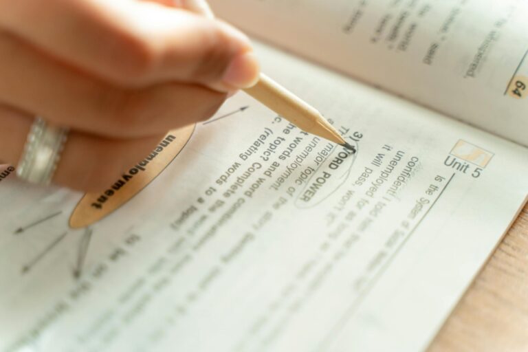 Close-up of a woman writing notes in a textbook, focusing on education and learning.