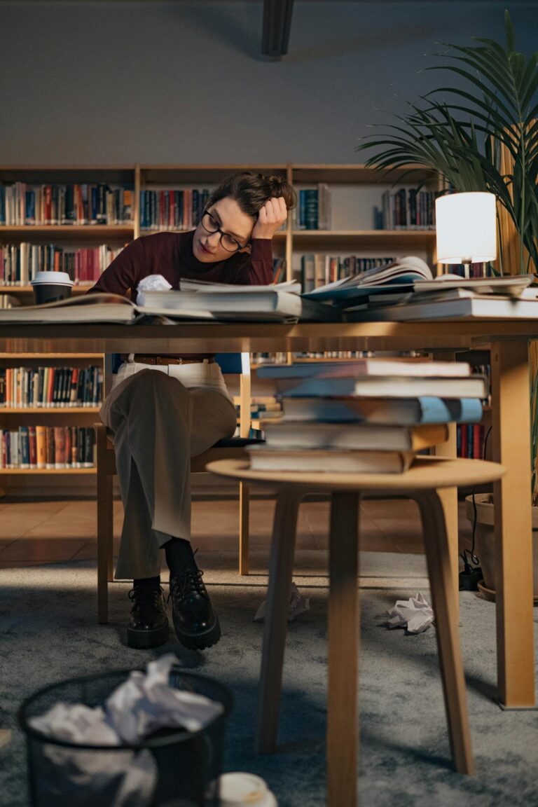 Woman intensely studying in a cozy library surrounded by books and notes.